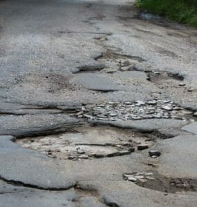 Pohľad na rozbitú cestu s výtlkmi