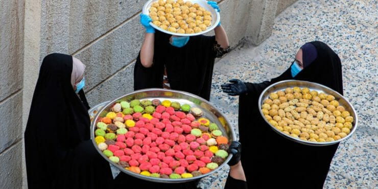 Iracké moslimské ženy s ochrannými rúškami nesú sladkosti pre veriacich na oslavu trojdňového sviatku íd al-fitr, konca pôstneho mesiaca ramadánu v Basre.