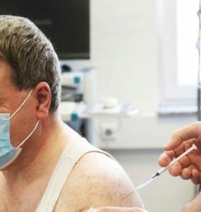 Zdravotník podáva vakcínu mužovi.