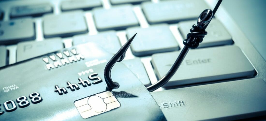 Bankomatová karta na klávesnici zaseknutá rybárskym háčikom.