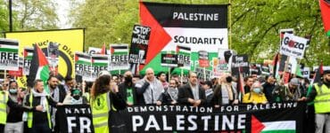Ľudia držia transparenty a palestínske zástavy pri pochodovaní počas protestu proti izraelským útokom na Palestínčanov v Gaze v Londýne 15. mája 2021.