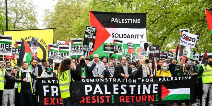 Ľudia držia transparenty a palestínske zástavy pri pochodovaní počas protestu proti izraelským útokom na Palestínčanov v Gaze v Londýne 15. mája 2021.
