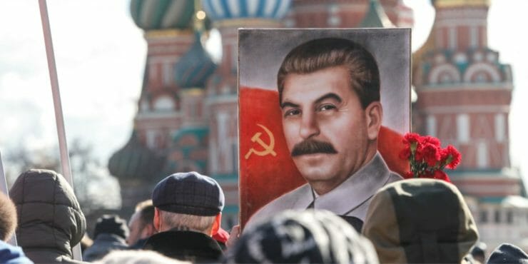 Priaznivci ruskej komunistickej strany s červenými zástavami a portrétom Josifa Vissarionoviča Stalina.