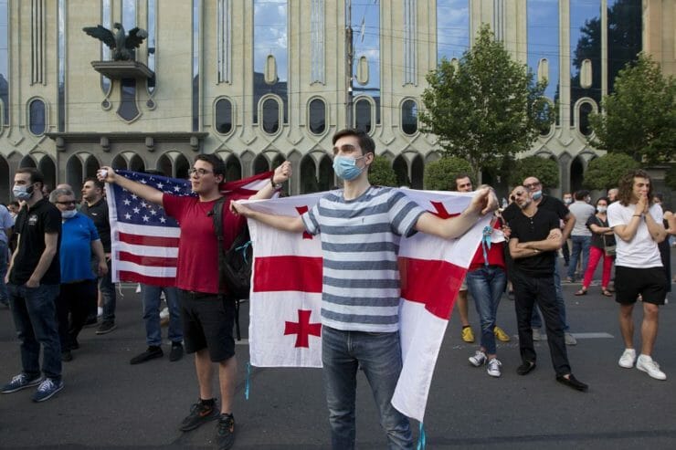 Ľudia stoja s gruzínskou a americkou vlajkou pred gruzínskym parlamentom 12. júla 2021 v Tbilisi.
