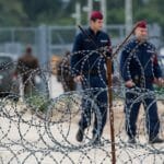 Maďarskí policajti hliadkujú pozdĺž plota s ostnatým drôtom