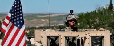 Americký vojak sedí na obrnenom vozidle.