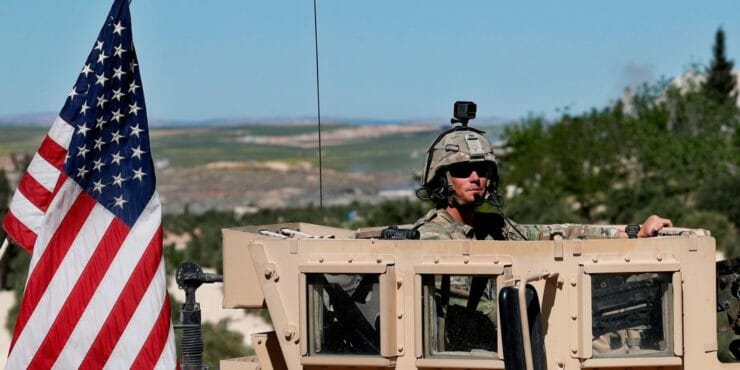 Americký vojak sedí na obrnenom vozidle.