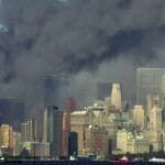 Na archívnej snímke z 11. septembra 2001 dym stúpa pred Sochou slobody z miesta pádu Svetového obchodného centra v New Yorku (WTC).