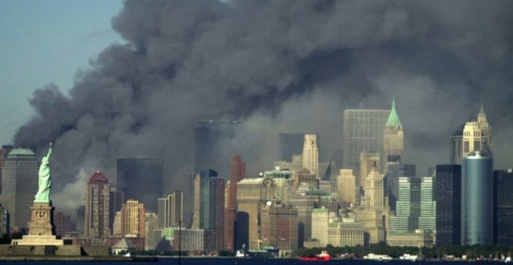 Na archívnej snímke z 11. septembra 2001 dym stúpa pred Sochou slobody z miesta pádu Svetového obchodného centra v New Yorku (WTC).