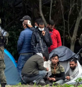 Migranti sedia po prekročení hranice z Bieloruska do Poľska v poľskej dedine Usnarz Gorny.