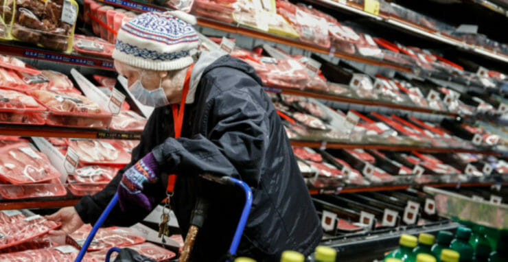 Seniorka s ochranným rúškom na tvári nakupuje mäso