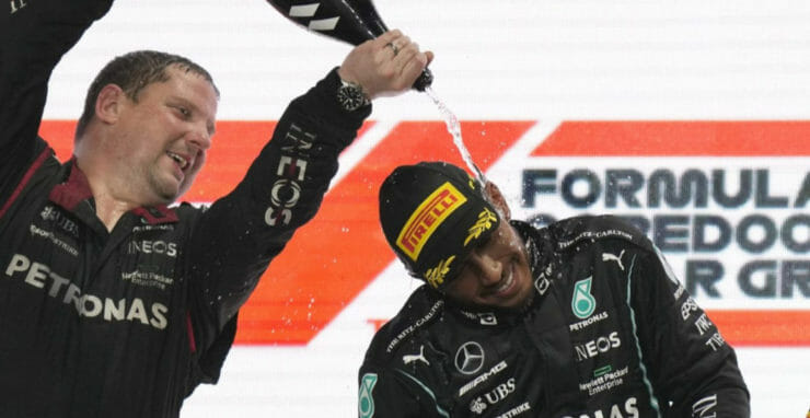 Britský pilot F1 Lewis Hamilton sa teší na pódiu s členom tímu.