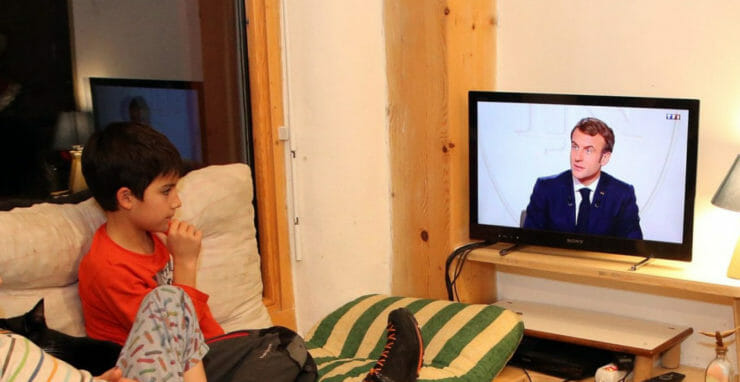 Rodina sleduje francúzskeho prezidenta Emmanuela Macrona počas televízneho rozhovoru v obci Ascain na juhozápade Francúzska v stredu 15.decembra 2021.