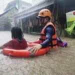 Záchranár pomáha dievčaťu, ktoré sa brodí po zaplavenej ulici počas vyčíňania tajfúnu Rai v meste Cagayan De Oro na juhu Filipín vo štvrtok 16. decembra 2021.