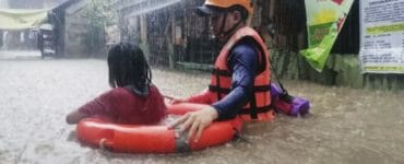 Záchranár pomáha dievčaťu, ktoré sa brodí po zaplavenej ulici počas vyčíňania tajfúnu Rai v meste Cagayan De Oro na juhu Filipín vo štvrtok 16. decembra 2021.
