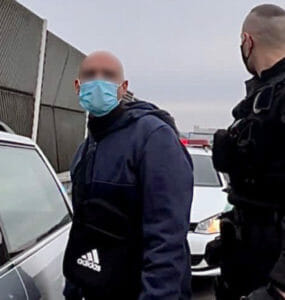 Policajt so zadržaným mužom, ktorý šoféroval prenasledované auto.