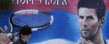ena kráča okolo nástennej maľby s podobizňou srbského tenistu Novaka Djokoviča v Belehrade v nedeľu 16. januára 2022.