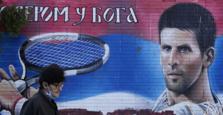 ena kráča okolo nástennej maľby s podobizňou srbského tenistu Novaka Djokoviča v Belehrade v nedeľu 16. januára 2022.