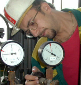 Pracovník teplárne kontroluje prístroje na turbogenerátore.