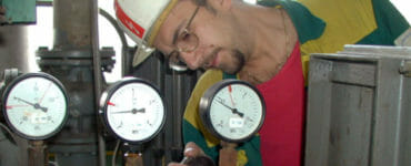Pracovník teplárne kontroluje prístroje na turbogenerátore.