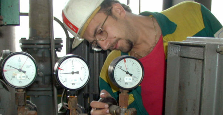 Pracovník teplárne kontroluje prístroje na turbogenerátore.