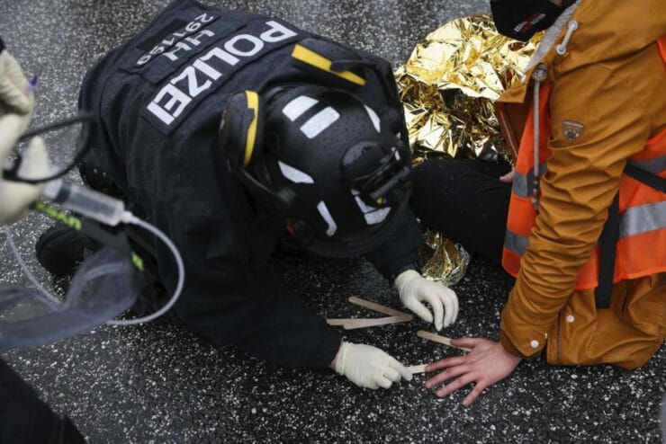Policajt v Hamburgu odstraňuje z asfaltu ruku aktivistu.