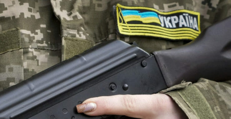 Príslušníčka civilnej obrany so zbraňou hliadkuje na prázdnej ulici kvôli zákazu vychádzania 27. februára 2022 v Kyjeve.