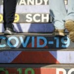 Ľudia kráčajú po schodoch s nápisom COVID-19 vo Viedni v piatok 4. februára 2022.