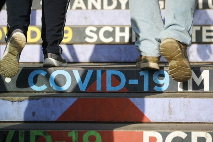 Ľudia kráčajú po schodoch s nápisom COVID-19 vo Viedni v piatok 4. februára 2022.