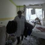 zdravotníčka kráča v zničenej budove pôrodnice po ostreľovaní v Mariupole
