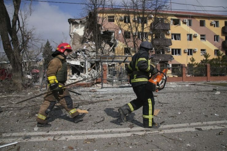 Hasiči kráčajú okolo zničenej budovy počas pätnásteho dňa ruskej invázie na Ukrajine vo štvrtok 10. marca 2022 v Mariupole.