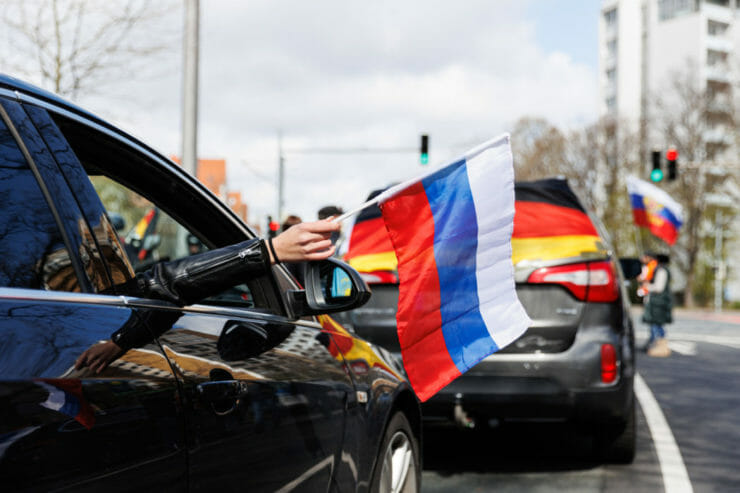 Žena drží ruskú vlajku z okna auta, ktoré je súčasťou dlhého konvoja počas proruského protestu v nemeckom meste Hannover v nedeľu 10. apríla 2022.