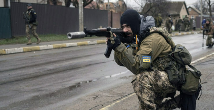 Na ilustračnej snímke ukrajinský vojak zabezpečuje presun spolubojovníkov počas kontroly nástražných pásc v meste Buča pri Kyjeve.