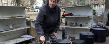 Na ilustračnej snímke žena varí na dvore poškodených bytoviek po ostreľovaní na okraji ukrajinského Mariupolu.