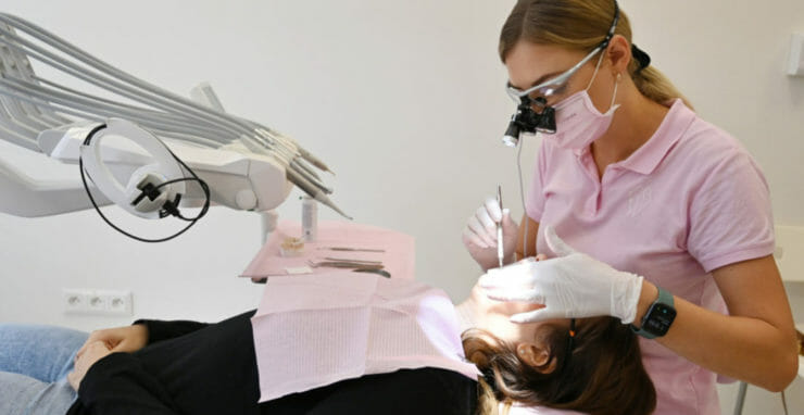 Na ilustračnej snímke zubná lekárka vykonáva zubársky zákrok pacientke.
