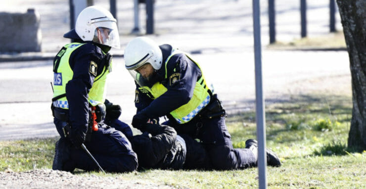 Policajti zatýkajú osobu počas nepokojov vo švédskom Norrköpingu v nedeľu 17. apríla 2022.
