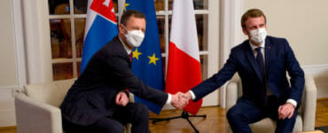 Emmanuel Macron (vpravo) a Eduard Heger (vľavo) si podávajú ruky v decembri 2021.