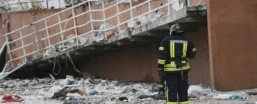 Na snímke hasič stojí vedľa obytného domu poškodeného ruským ostreľovaním v Odese na Ukrajine v sobotu 23. apríla 2022.