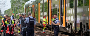 Policajti stoja pred regionálnym vlakom Euroregio v nemeckom meste Aachen v piatok 13. mája 2022.
