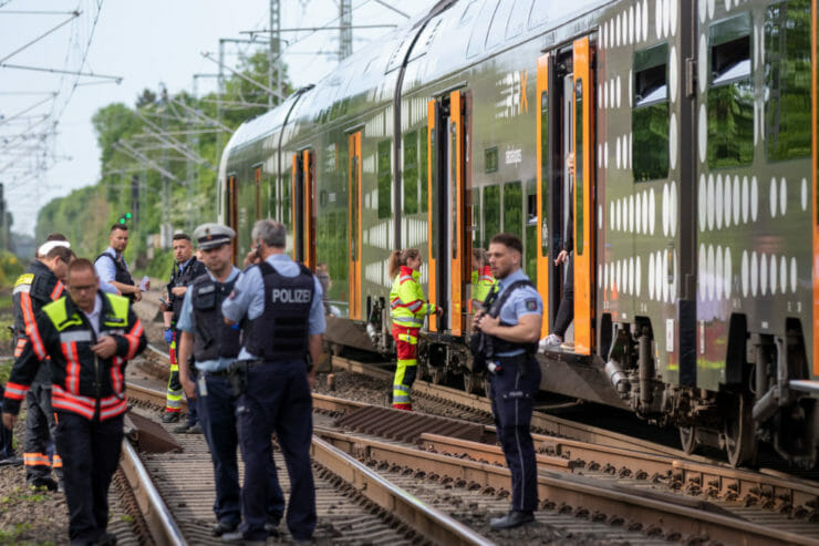 Policajti stoja pred regionálnym vlakom Euroregio v nemeckom meste Aachen v piatok 13. mája 2022.