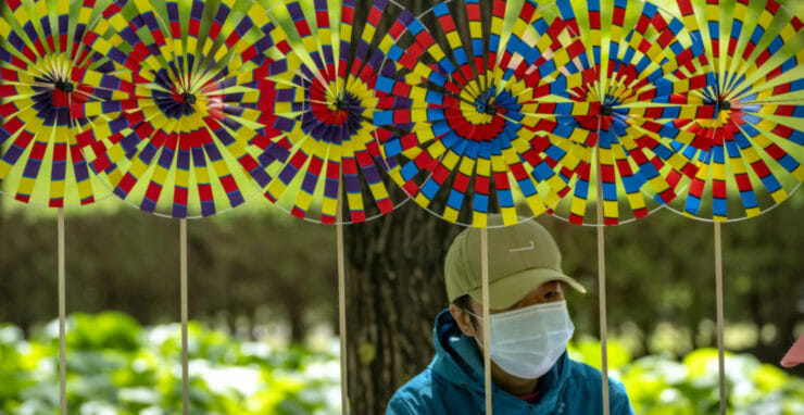 Pouličný predavač s ochranným rúškom predáva rôzne vrtuľky vo verejnom parku v Pekingu 3. mája 2022.