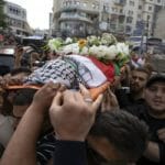 Na archívnej snímke z 11. mája 2022 Palestínčania nesú rakvu s pozostatkami novinárky televízie al-Džazíra Šírín abú Aklaovej v uliciach Ramalláhu