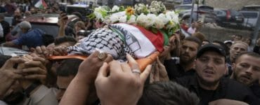 Na archívnej snímke z 11. mája 2022 Palestínčania nesú rakvu s pozostatkami novinárky televízie al-Džazíra Šírín abú Aklaovej v uliciach Ramalláhu