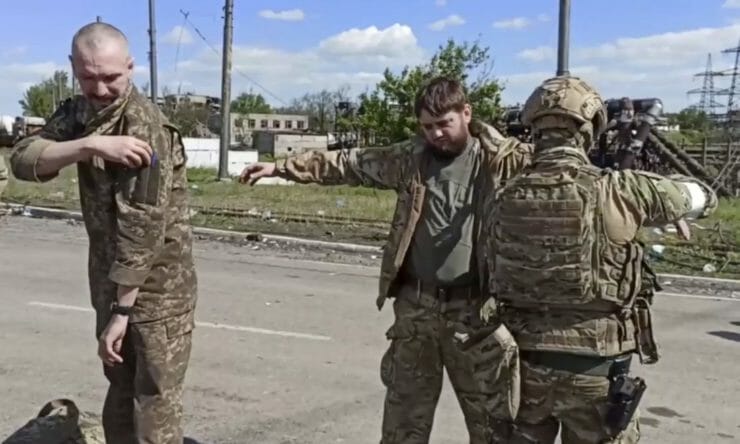Na ilustračnej snímke z videa ruský vojak (vpravo) prehľadáva ukrajinských bojovníkov z Azovstaľu.