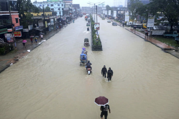 Ľudia sa brodia po zaplavenej ulici v meste Silét na severovýchode Bangladéša v sobotu 18. júna 2022.