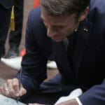 Emmanuel Macron sa podpisuje chlapcovi na jeho sadru pred príchodom do volebnej miestnosti v obci Le Touquet.