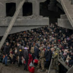 Na archívnej snímke z 5. marca 2022 ľudia, ktorí utekajú počas vojny zo svojich domovov, sa zhromaždili pod zničeným mostom pri rieke Irpiň na predmestí Kyjeva.