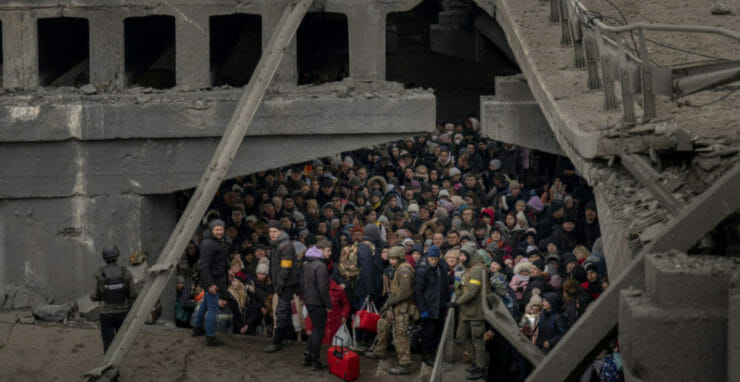 Na archívnej snímke z 5. marca 2022 ľudia, ktorí utekajú počas vojny zo svojich domovov, sa zhromaždili pod zničeným mostom pri rieke Irpiň na predmestí Kyjeva.