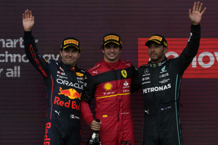 Carlos Sainz (uprostred) z tímu Ferrari pózuje po víťazstve. Druhé miesto obsadil Sergio Perez (vľavo) a tretí skončil domáci Lewis Hamilton (vpravo).