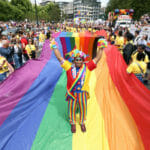 Mohammed Nazir z Londýna pózuje na veľkej dúhovej vlajke pred začiatkom londýnskeho pochodu Pride pri príležitosti 50. výročia hnutia Pride v Británii v Londýne 2. júla 2022.